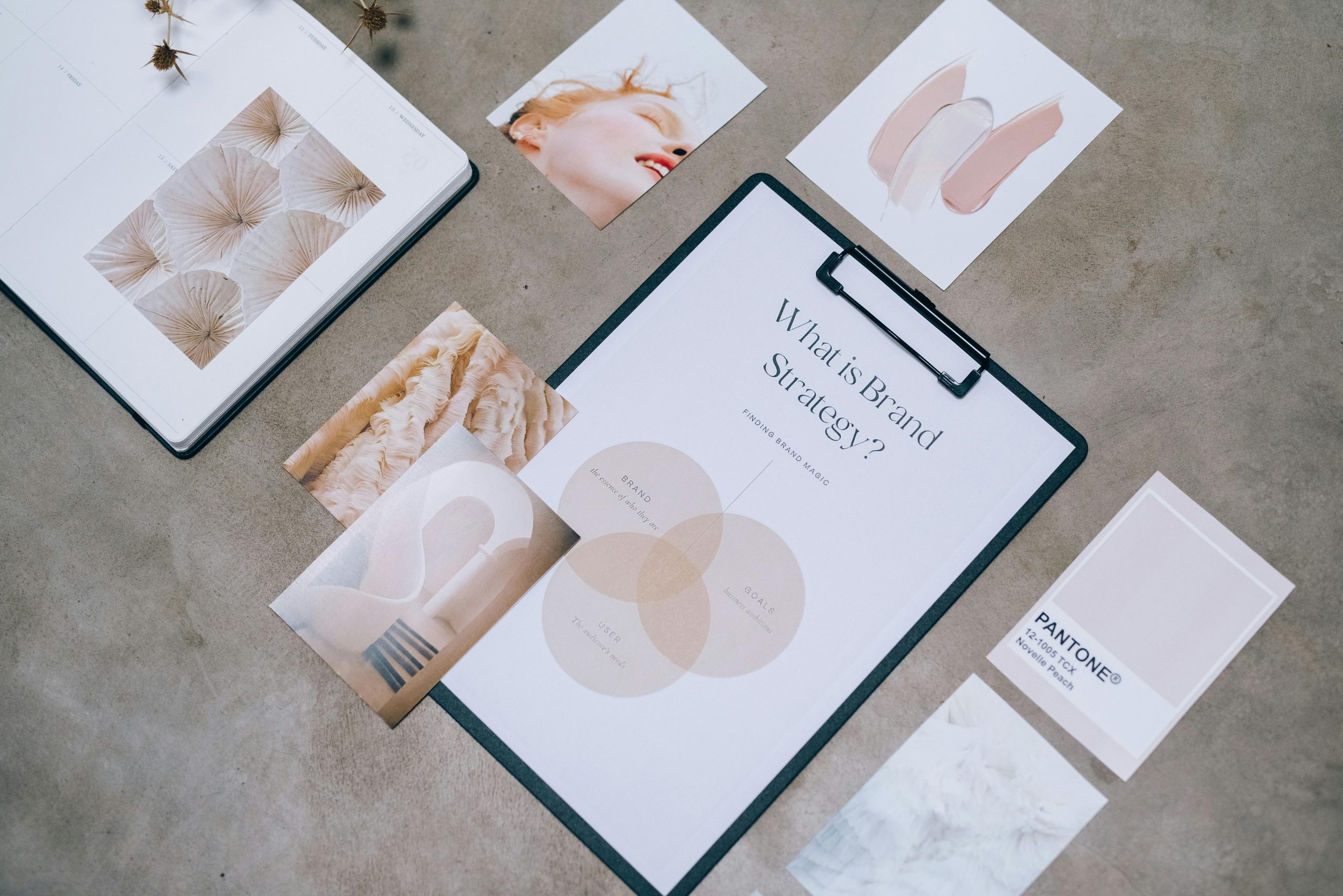 A flat-lay image of a desk showcasing a moodboard and printed marketing materials, including documents titled 'Brand Strategy,' arranged neatly to convey a thoughtful and creative planning process.
